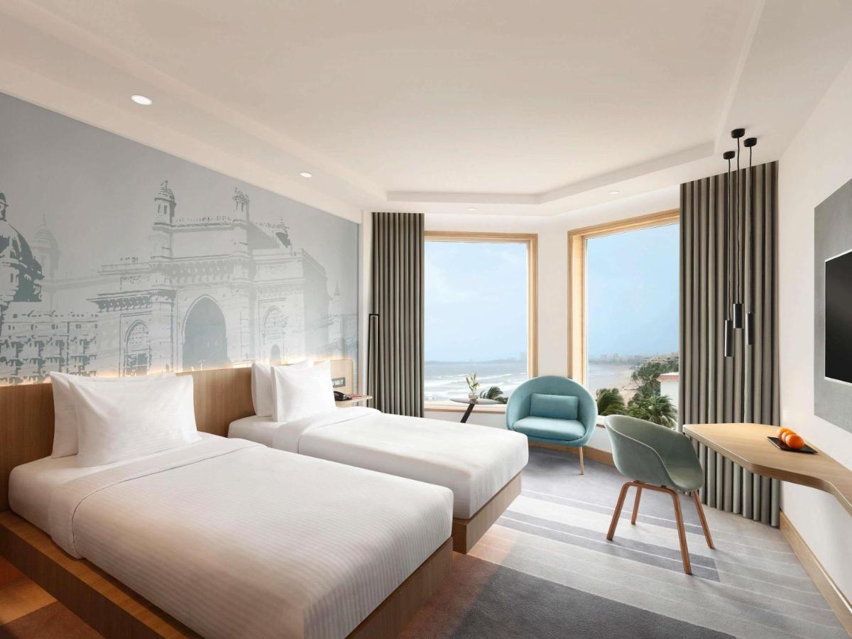a hotel room with two beds and a tv at Novotel Mumbai Juhu Beach in Mumbai