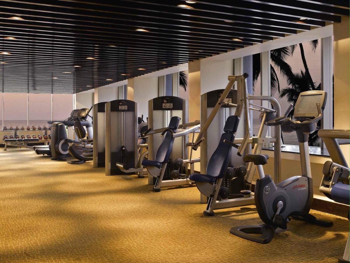 a gym with a row of treadms and cardio machines at Novotel Mumbai Juhu Beach in Mumbai