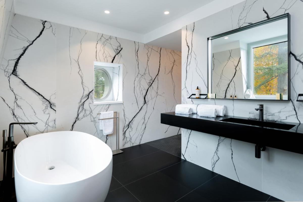 une salle de bains avec une baignoire blanche et un miroir dans l'établissement Hôtel Spa Restaurant Villa Castellane, à Gréoux-les-Bains
