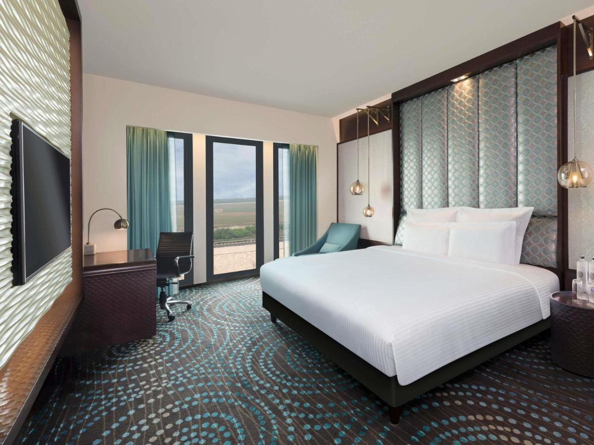 a hotel room with a large white bed and windows at Pullman New Delhi Aerocity in New Delhi