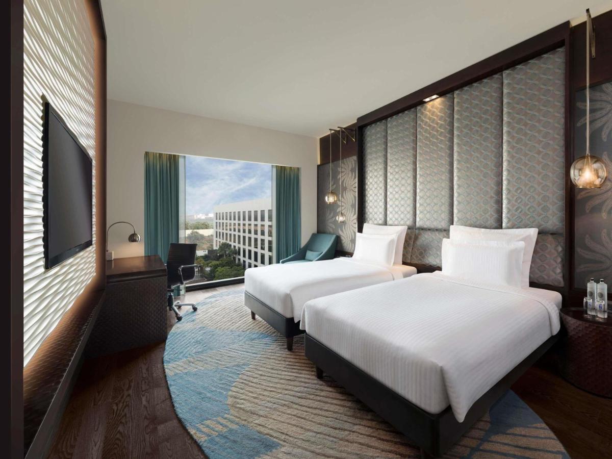 a hotel room with two beds and a large window at Pullman New Delhi Aerocity in New Delhi
