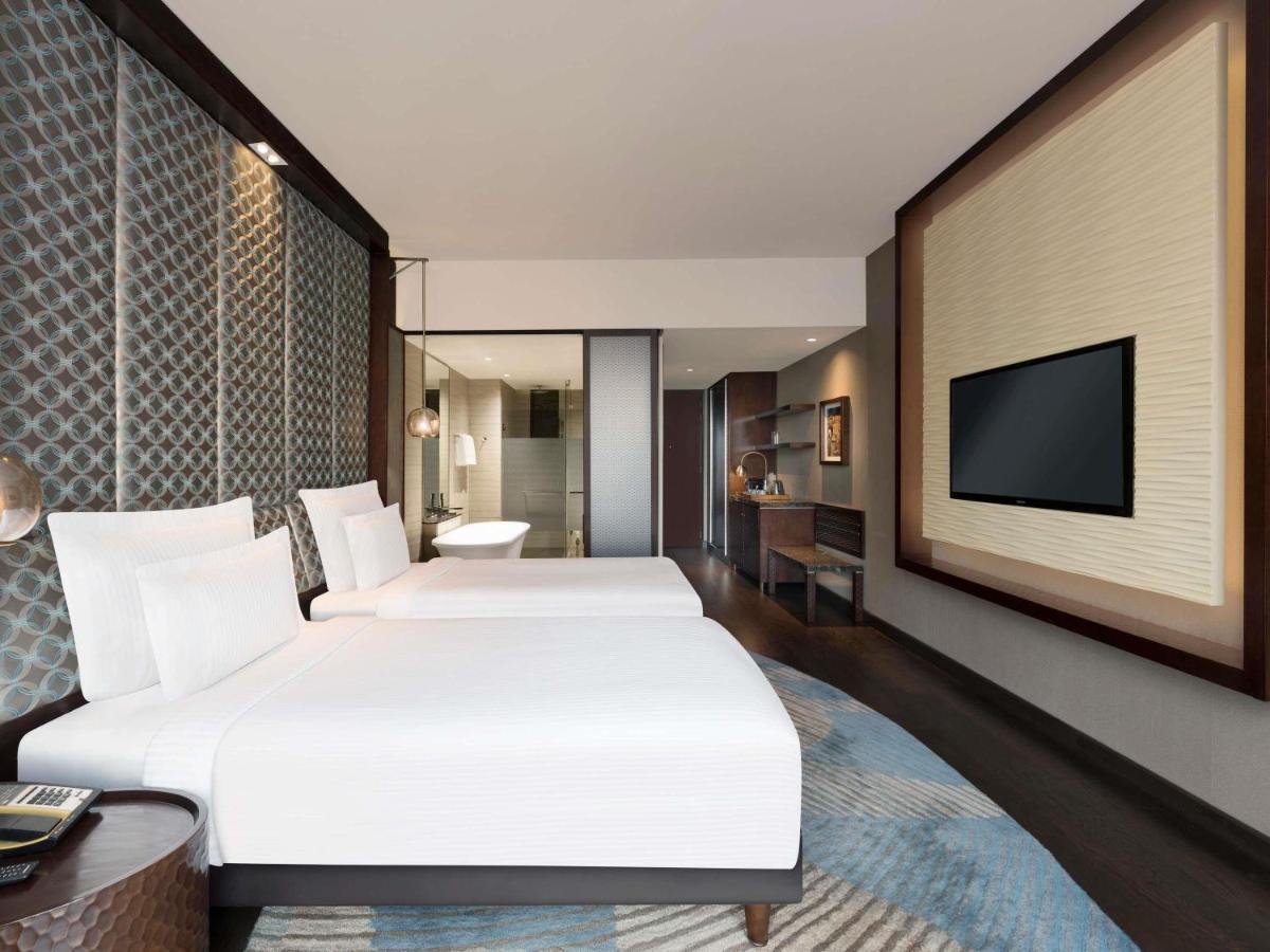 a hotel room with two beds and a flat screen tv at Pullman New Delhi Aerocity in New Delhi