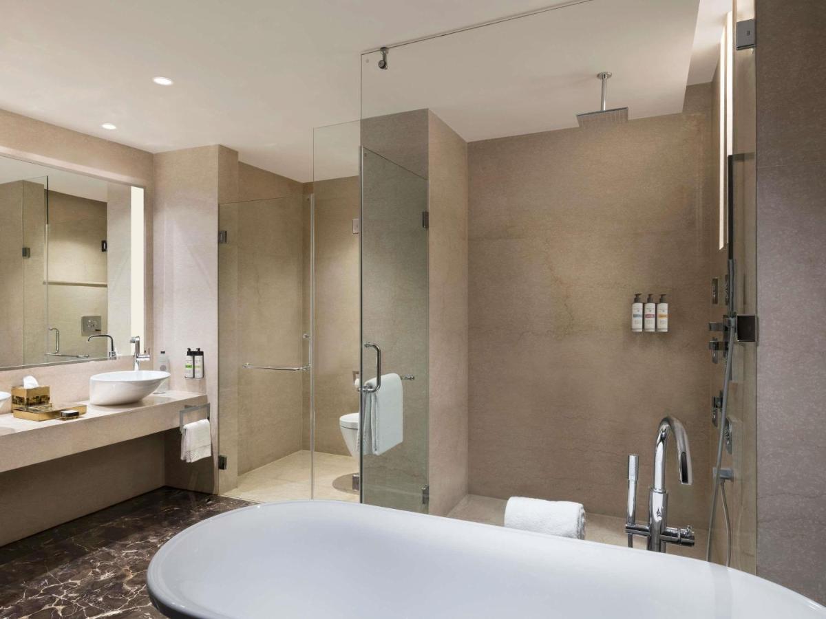 a bathroom with a tub and a glass shower at Pullman New Delhi Aerocity in New Delhi
