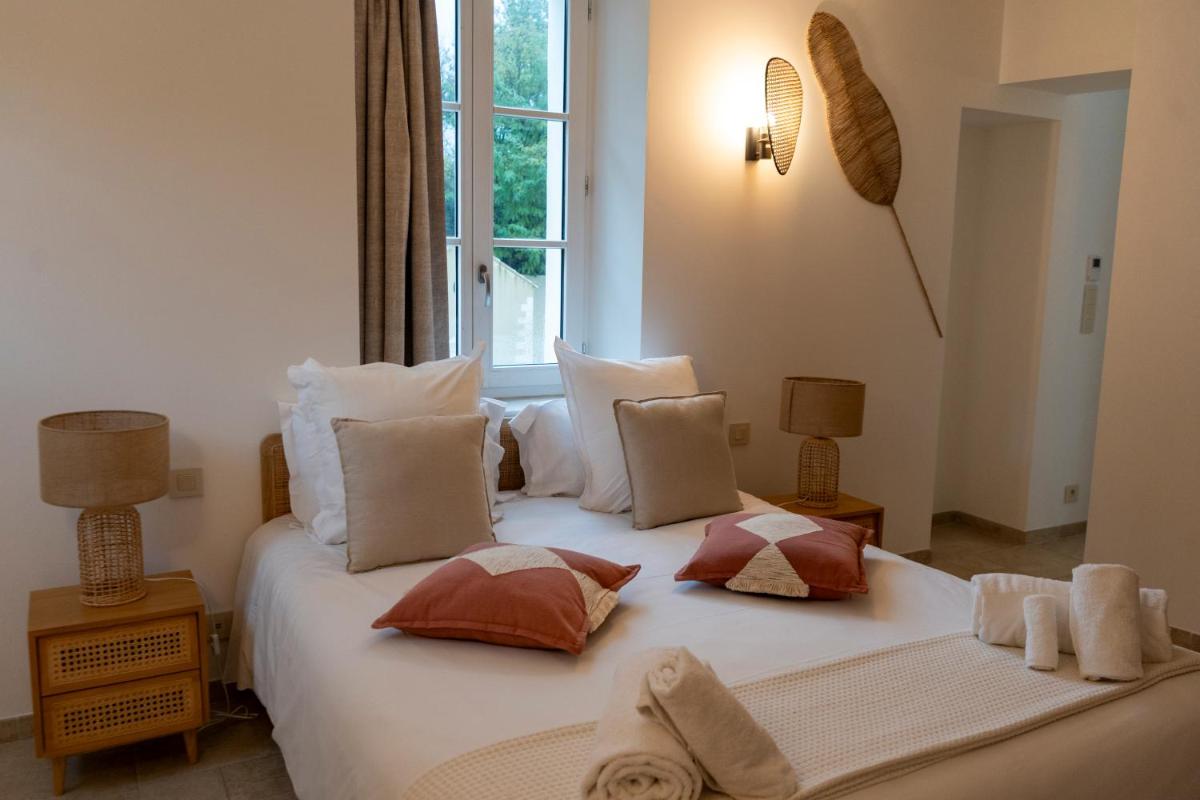 une chambre avec un grand lit blanc et des oreillers dans l'établissement Château de l'insolas, à Villeneuve-lès-Avignon