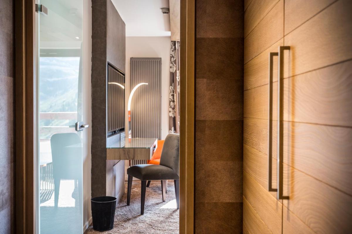 Cette chambre comprend un bureau, une chaise et une porte. dans l'établissement Hôtel Taj-I Mah by Les Etincelles, à Arc 2000