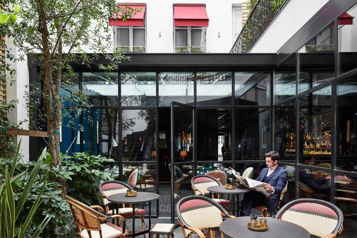 un homme assis à une table dans un restaurant dans l'établissement Le Roch Hotel & Spa, à Paris