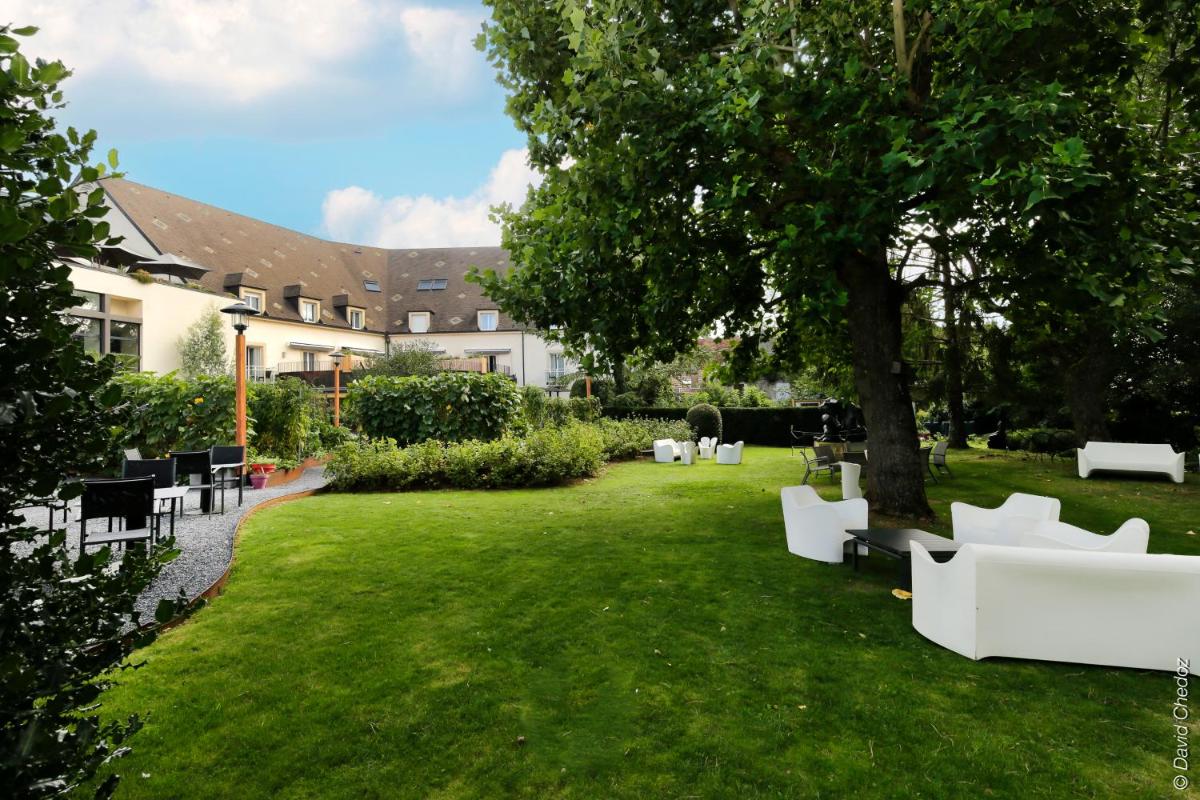 un jardin avec des meubles blancs et un arbre dans l'établissement Le Richebourg Hôtel, Restaurant & Spa, à Vosne-Romanée