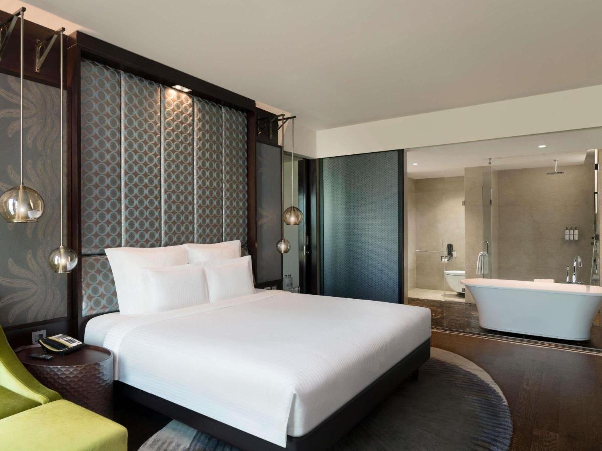 a bedroom with a large bed and a bath tub at Pullman New Delhi Aerocity in New Delhi