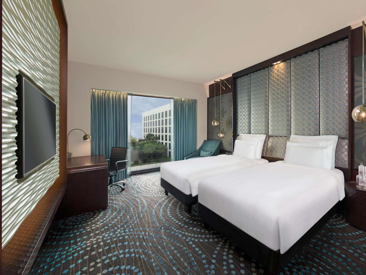 a hotel room with two beds and a large window at Pullman New Delhi Aerocity in New Delhi