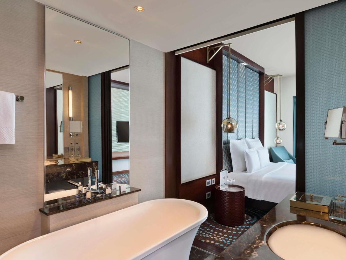 a bathroom with a tub and a bedroom with a bed at Pullman New Delhi Aerocity in New Delhi
