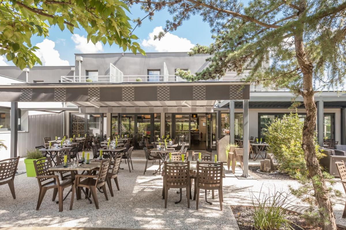 une terrasse extérieure avec tables et chaises devant un bâtiment dans l'établissement Logis Hotel Restaurant & SPA Au Comte d'Ornon, à Gradignan