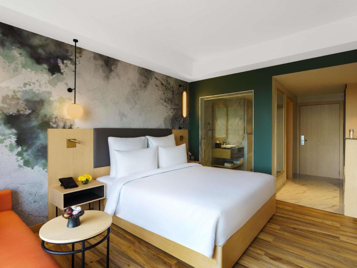 a bedroom with a large white bed and a couch at Novotel Jaipur Convention Centre in Jaipur