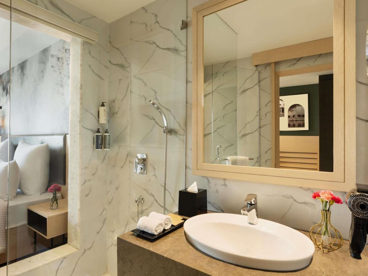 a white bathroom with a sink and a shower at Novotel Jaipur Convention Centre in Jaipur