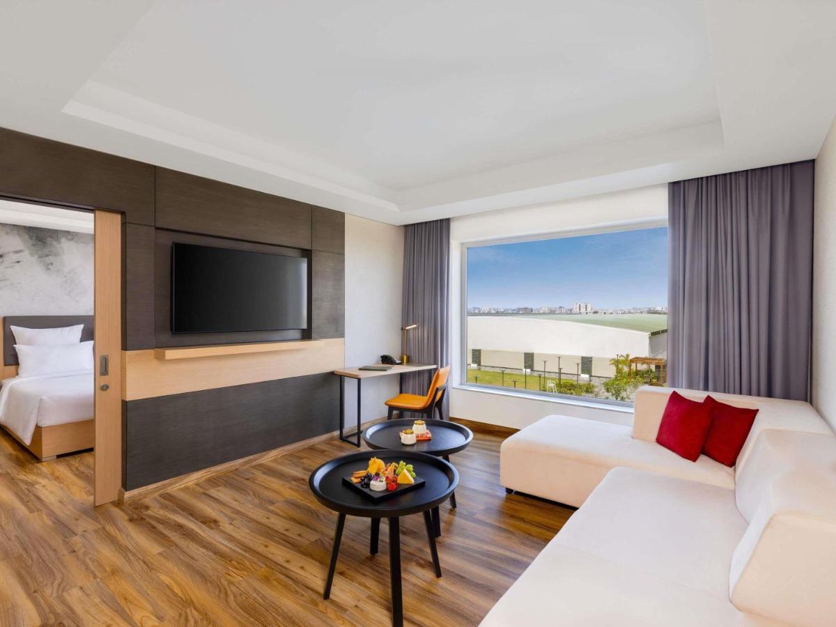 a hotel room with a couch and a tv at Novotel Jaipur Convention Centre in Jaipur