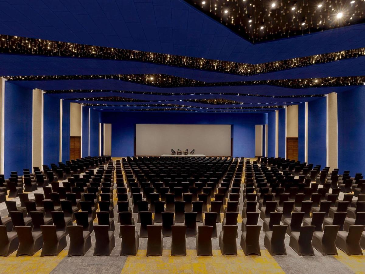 a large room with a stage with chairs and a screen at Novotel Jaipur Convention Centre in Jaipur