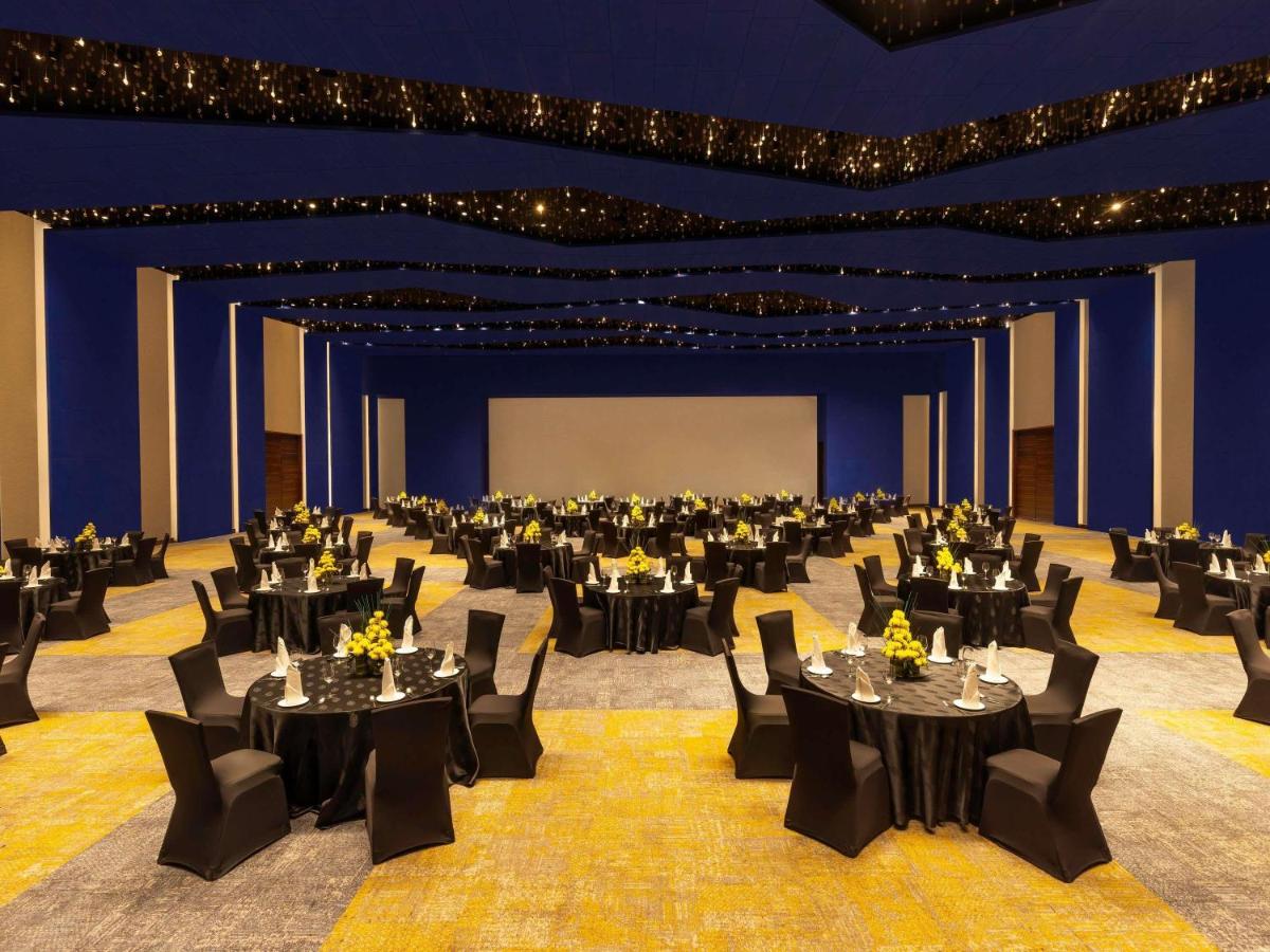a large banquet hall with black tables and chairs at Novotel Jaipur Convention Centre in Jaipur