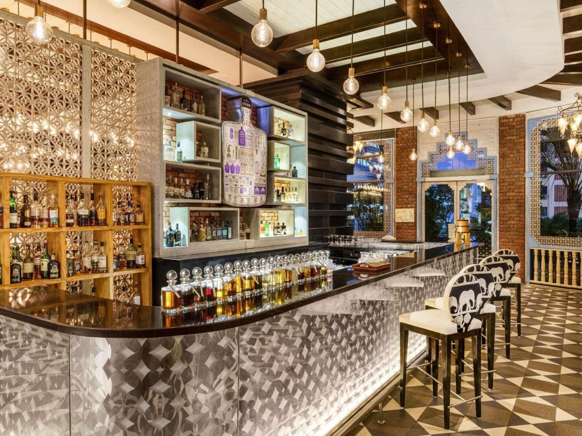 a bar with bar stools and bottles of alcohol at Sofitel Mumbai BKC in Mumbai
