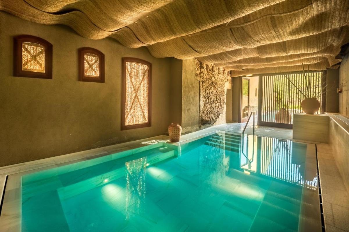 una piscina cubierta con agua azul en una casa en Mas Salagros EcoResort & SPA, en Vallromanes