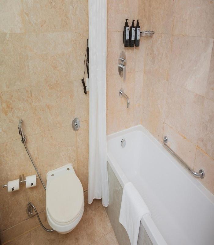 a bathroom with a white toilet and a bath tub at The Park New Delhi in New Delhi a bathroom with a white toilet and a bath tub at The Park New Delhi in New Delhi