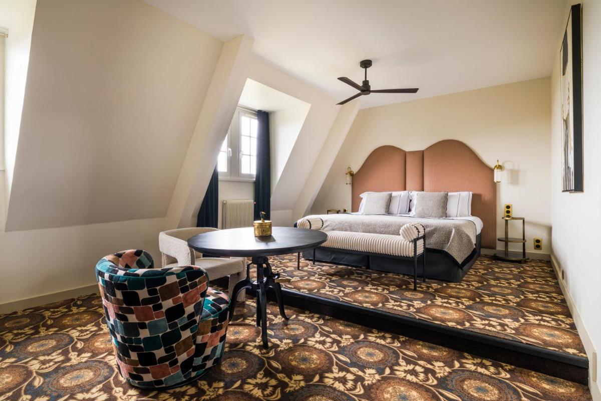 une chambre avec un lit, une table et des chaises dans l'établissement Château Jeanne & The Forest - Château de Montvillargenne, à Gouvieux