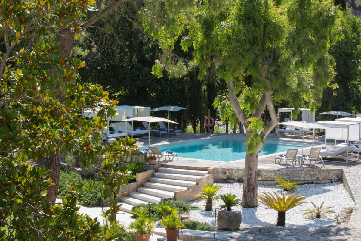 una piscina con mesas, sillas y árboles en L’Hermitage Hotel & Spa, en Orient