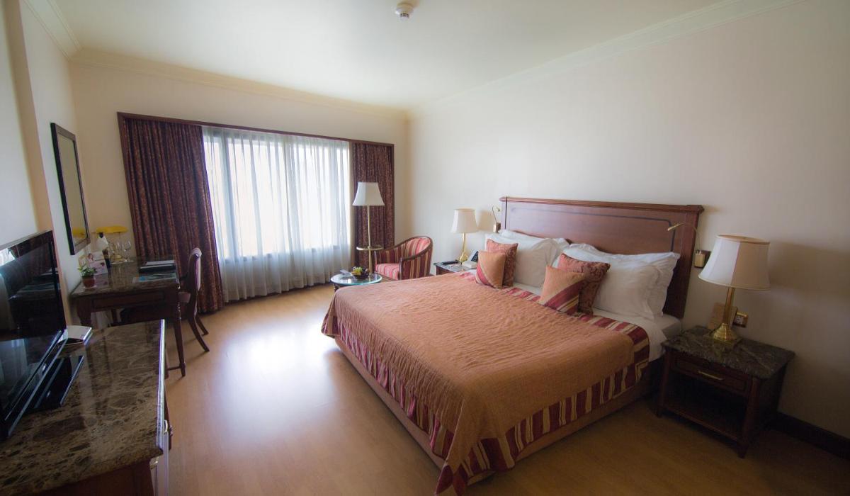 a hotel room with a bed and a television at The Orchid Hotel Mumbai Vile Parle in Mumbai