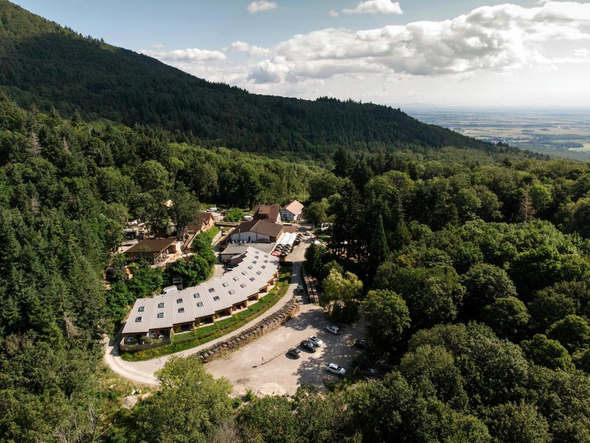 une vue aérienne d'un bâtiment au milieu d'une montagne dans l'établissement Domaine du Hirtz, Restaurant & Spa, à Wattwiller