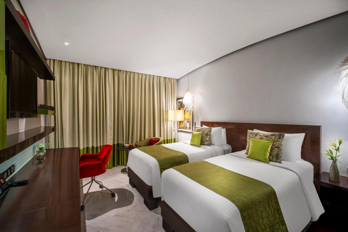 a hotel room with two beds and a red chair at The Park Chennai in Chennai