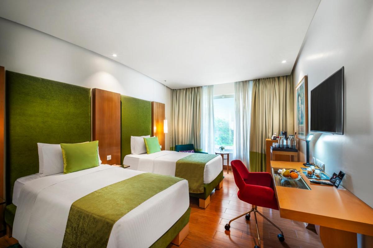a hotel room with two beds and a desk at The Park Chennai in Chennai