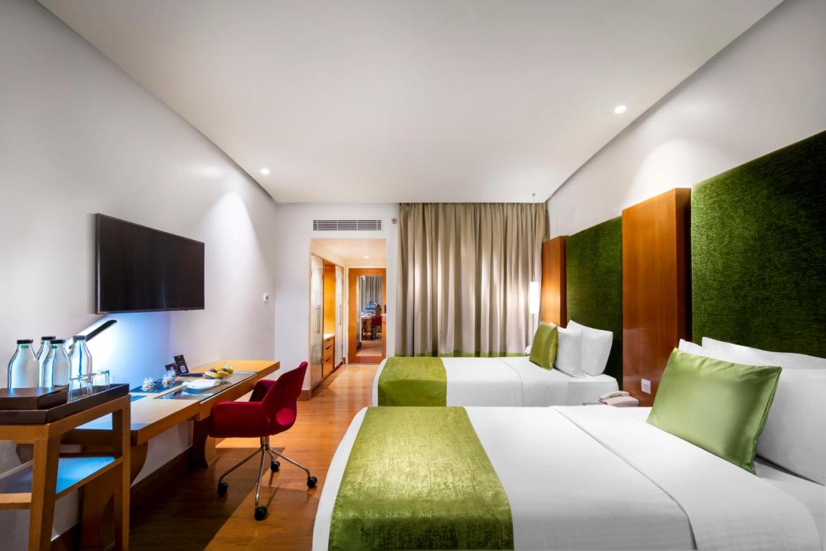 a hotel room with two beds and a desk at The Park Chennai in Chennai