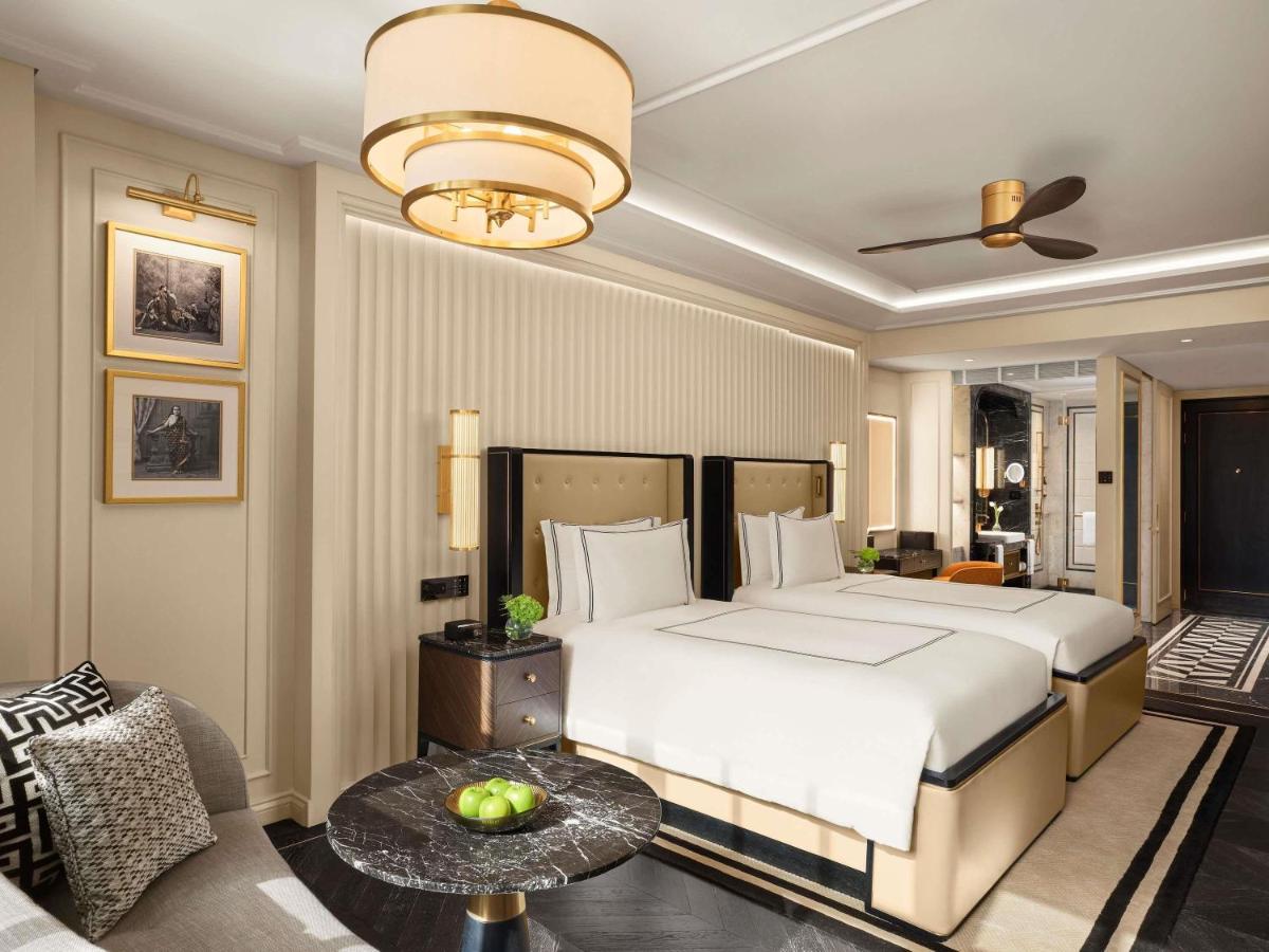 a bedroom with a large bed and a living room at Fairmont Mumbai in Mumbai