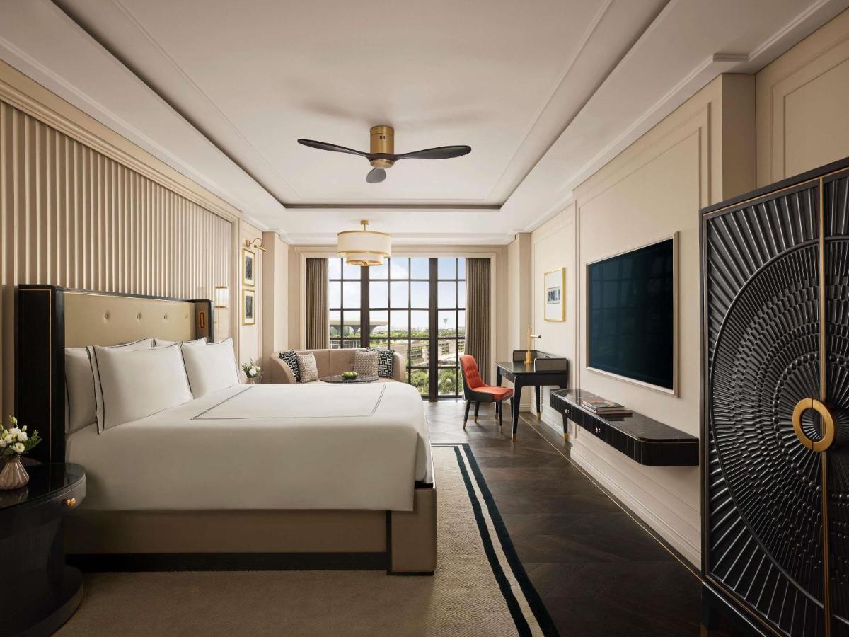a bedroom with a bed and a desk and a television at Fairmont Mumbai in Mumbai