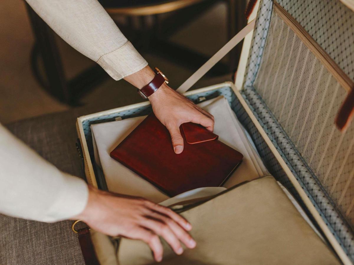 a person holding a wallet in an open suitcase at Fairmont Mumbai in Mumbai