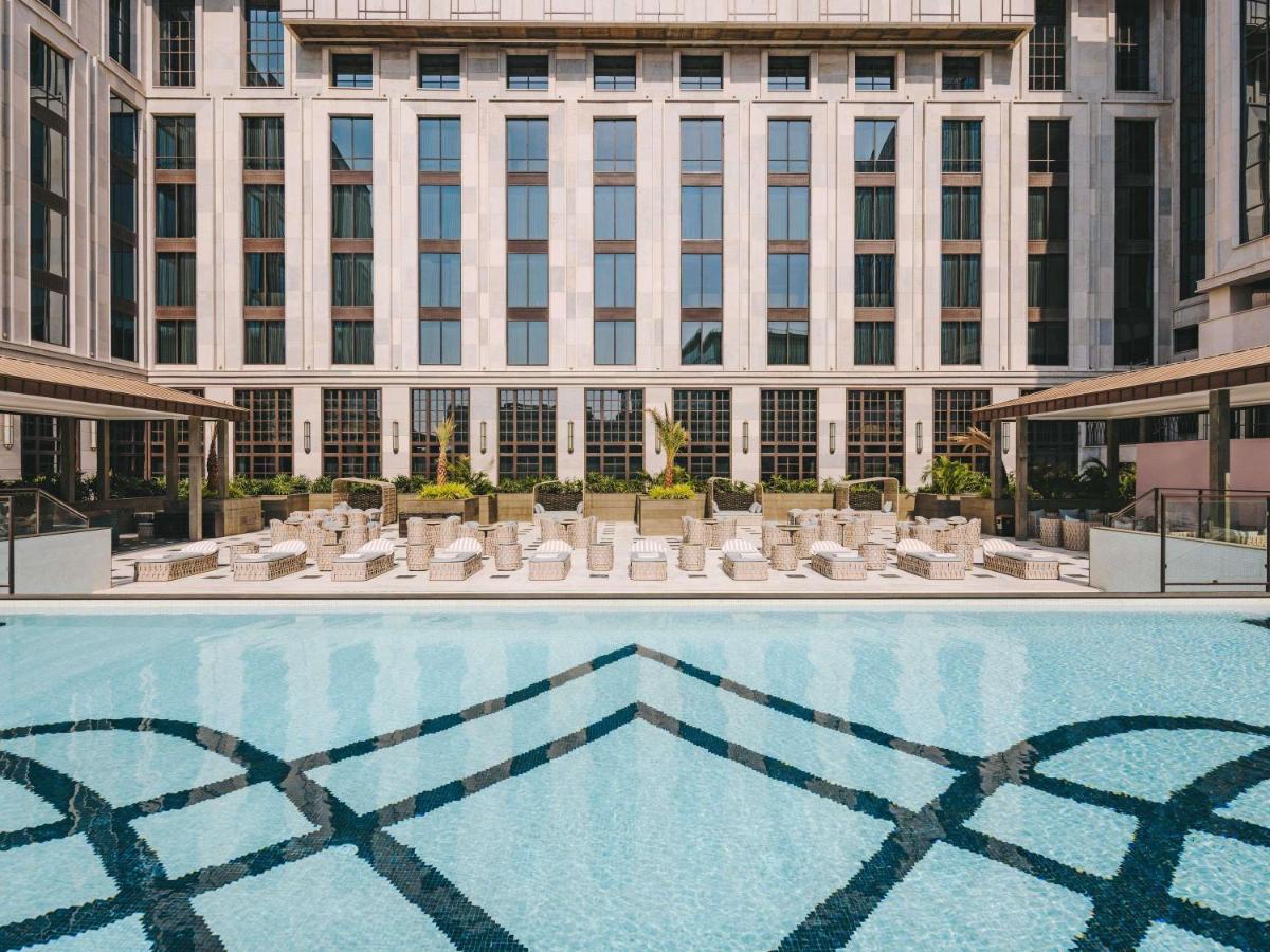 a swimming pool with chairs and a building at Fairmont Mumbai in Mumbai