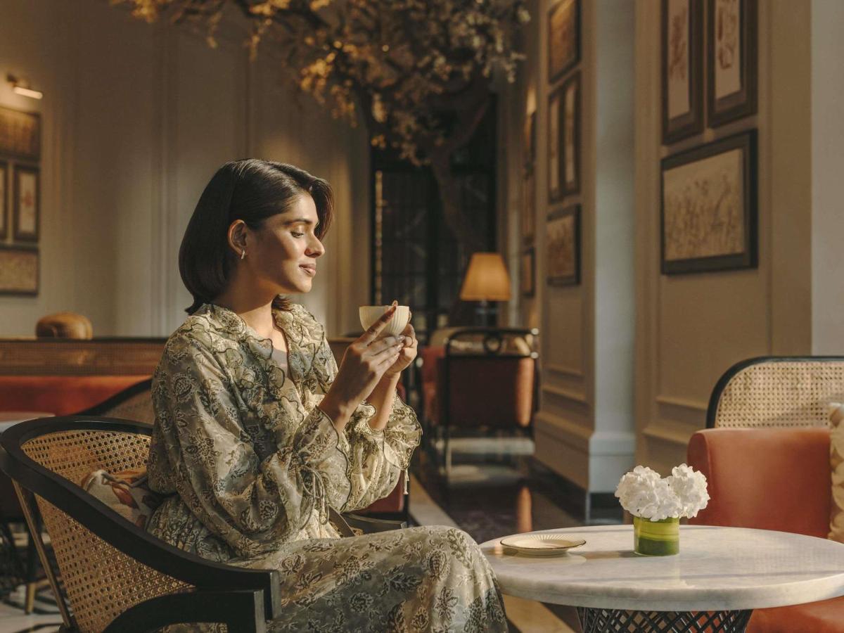 a woman sitting in a chair holding a cup at Fairmont Mumbai in Mumbai