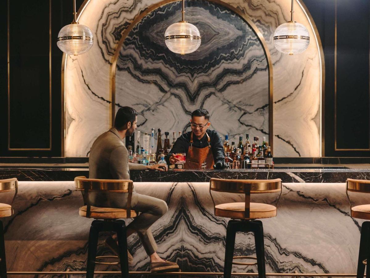 a man sitting at a bar in front of a mirror at Fairmont Mumbai in Mumbai