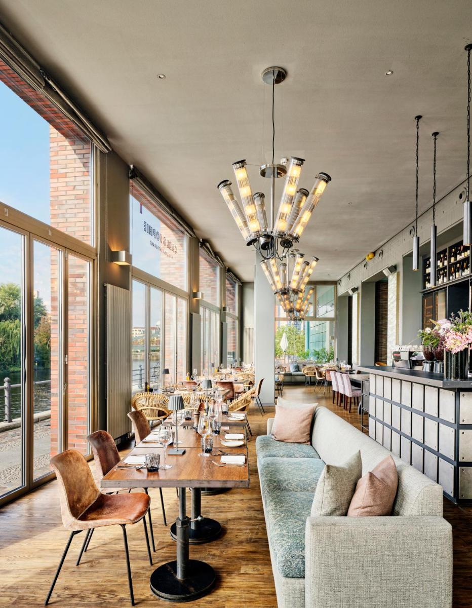 ein Restaurant mit Sofa, Tischen und Fenstern in der Unterkunft ABION Villa Suites in Berlin