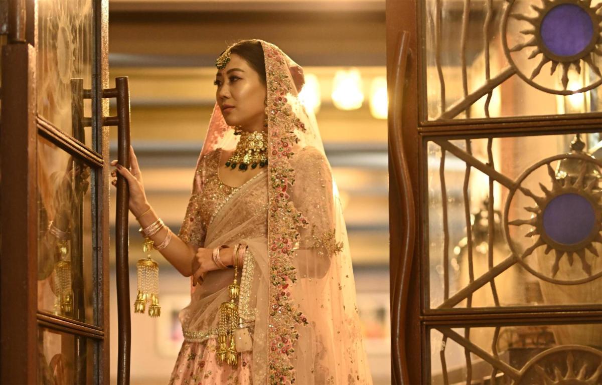 a woman in a peach dress looking out a window at Radisson Blu Hotel Pune Kharadi in Pune