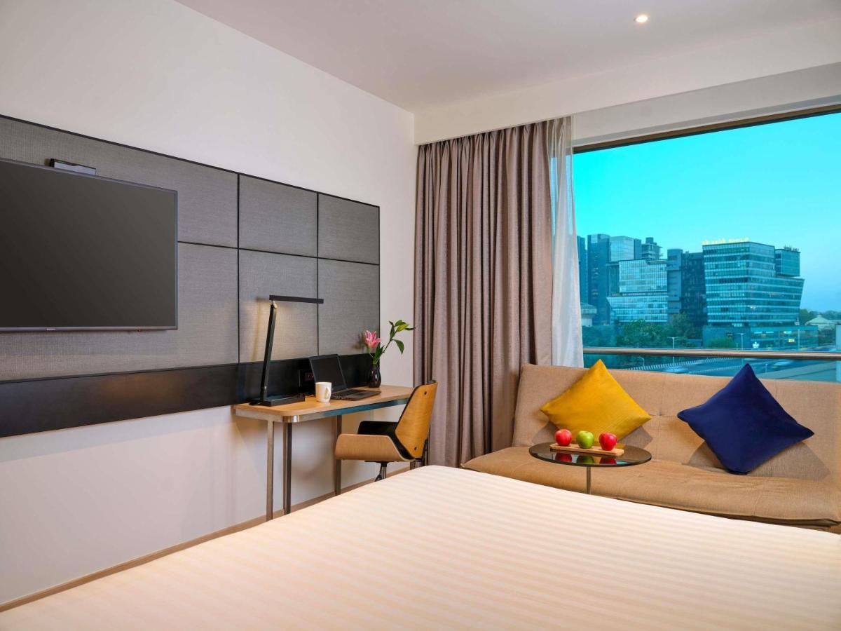 a hotel room with a bed and a tv at Novotel Ahmedabad in Ahmedabad