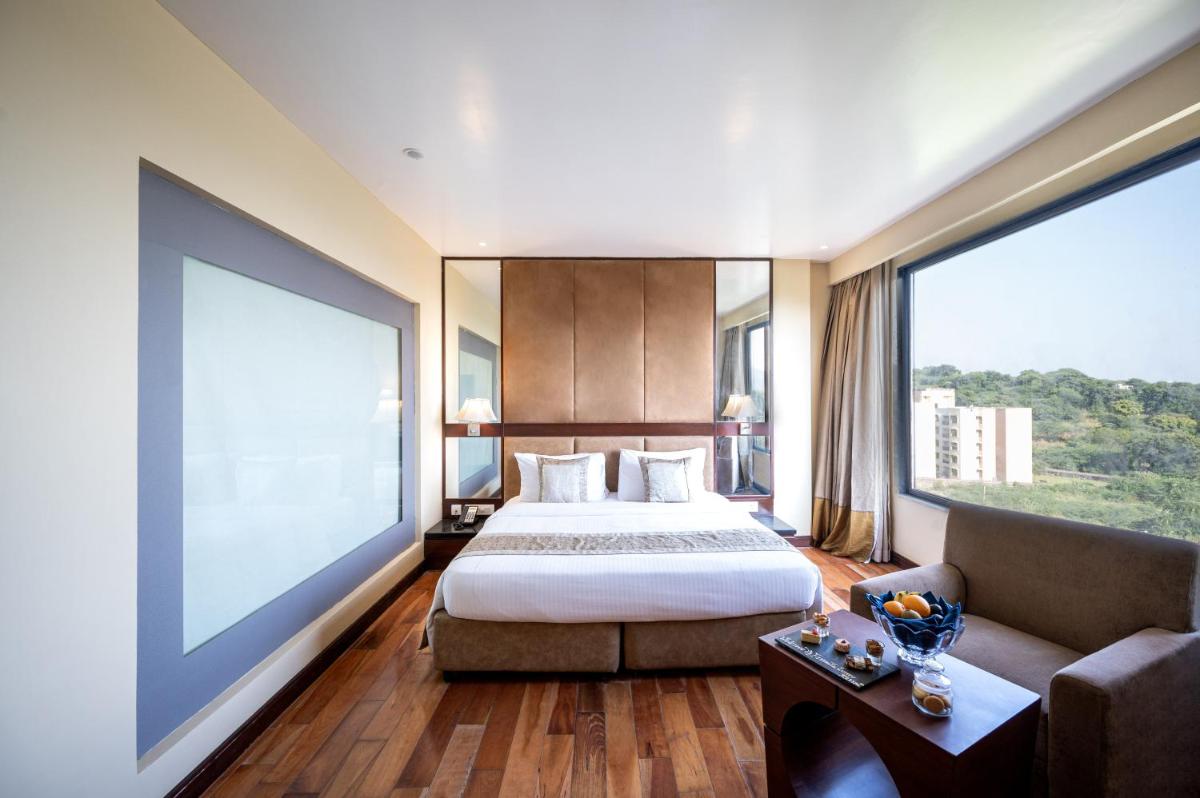 a bedroom with a bed and a couch and a large window at Essentia Luxury Resort & Spa Udaipur in Udaipur