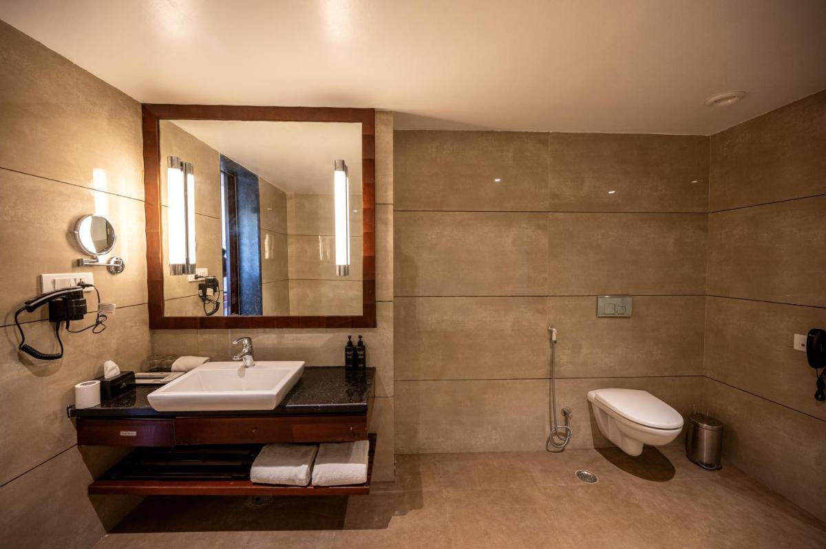 a bathroom with a sink and a toilet and a mirror at Essentia Luxury Resort & Spa Udaipur in Udaipur