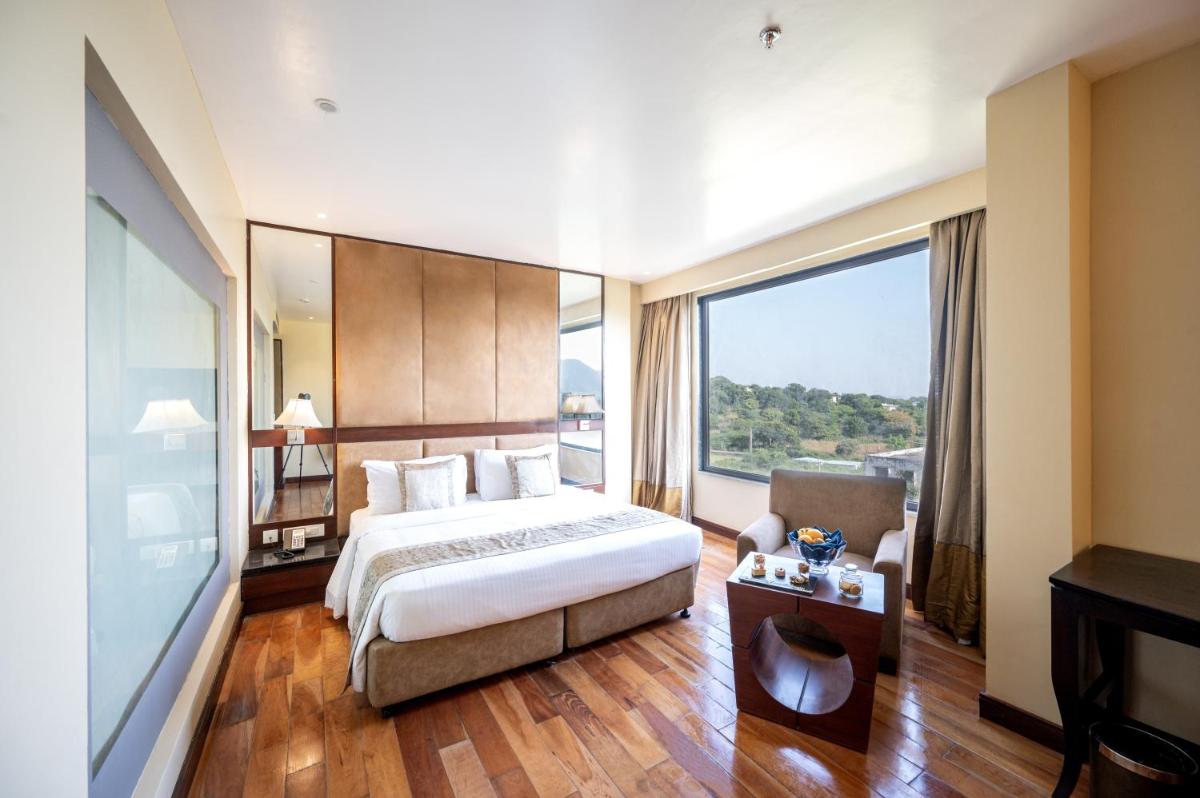 a hotel room with a bed and a large window at Essentia Luxury Resort & Spa Udaipur in Udaipur