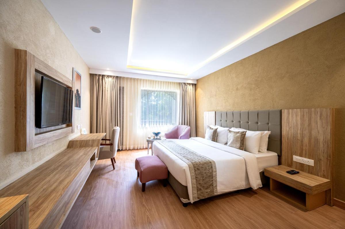 a hotel room with a bed and a television at Essentia Luxury Resort & Spa Udaipur in Udaipur