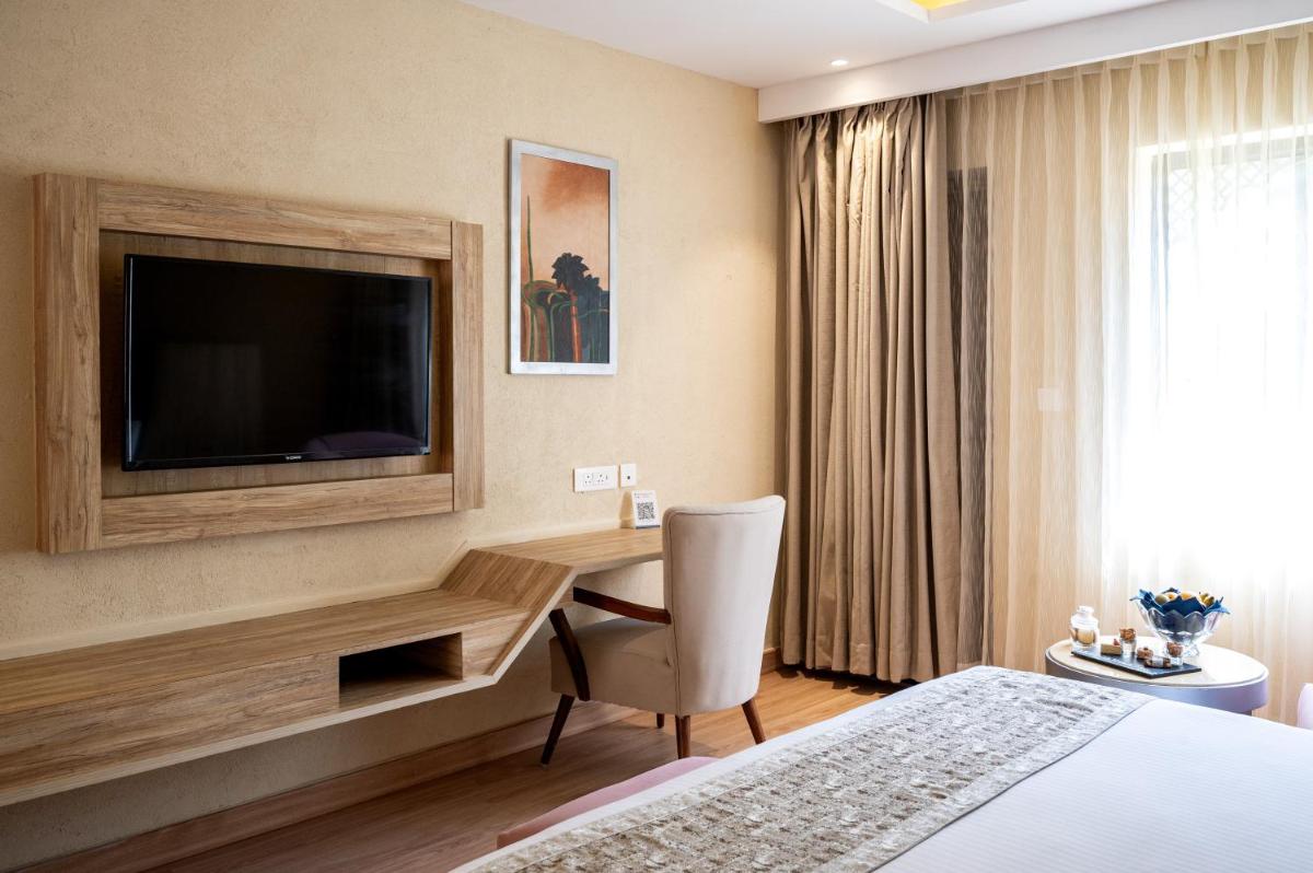 a hotel room with a desk and a television at Essentia Luxury Resort & Spa Udaipur in Udaipur