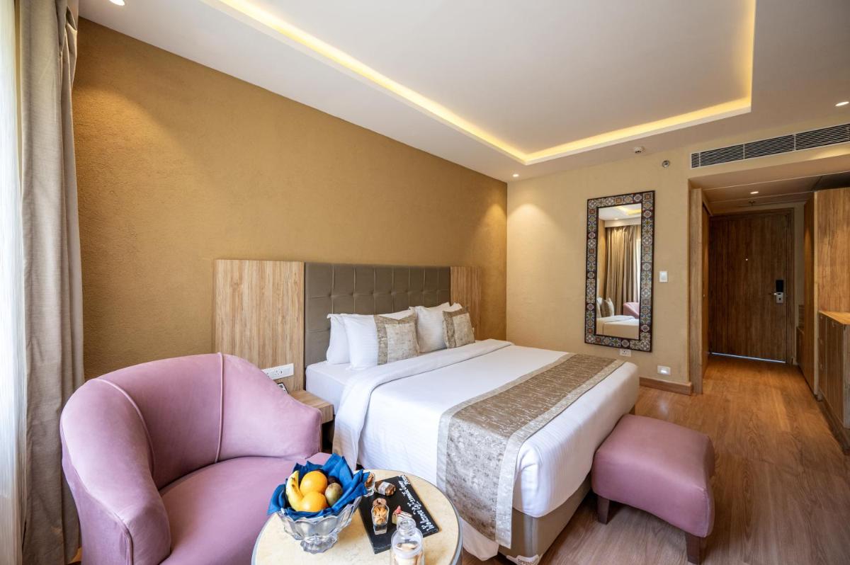 a hotel room with a bed and a chair at Essentia Luxury Resort & Spa Udaipur in Udaipur
