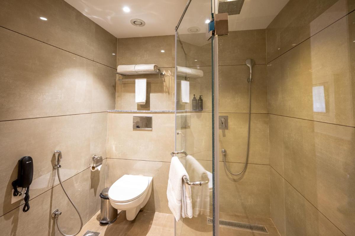 a bathroom with a shower with a toilet and a glass door at Essentia Luxury Resort & Spa Udaipur in Udaipur