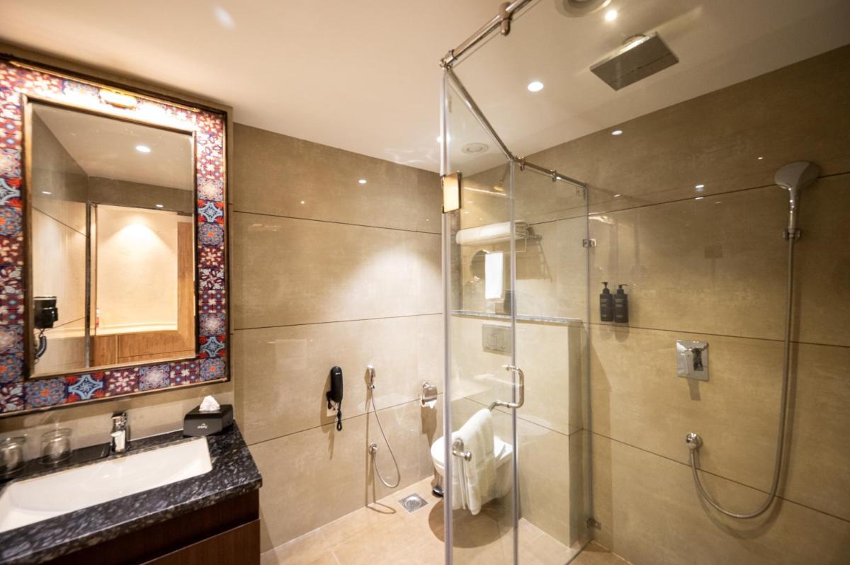 a bathroom with a shower and a sink and a mirror at Essentia Luxury Resort & Spa Udaipur in Udaipur