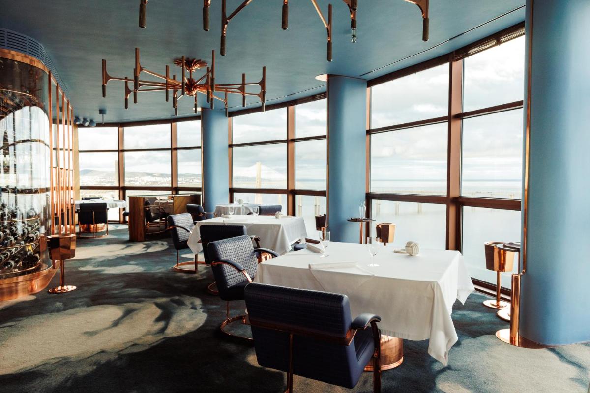 uma sala de jantar com mesas, cadeiras e janelas em MYRIAD by SANA Hotels em Lisboa