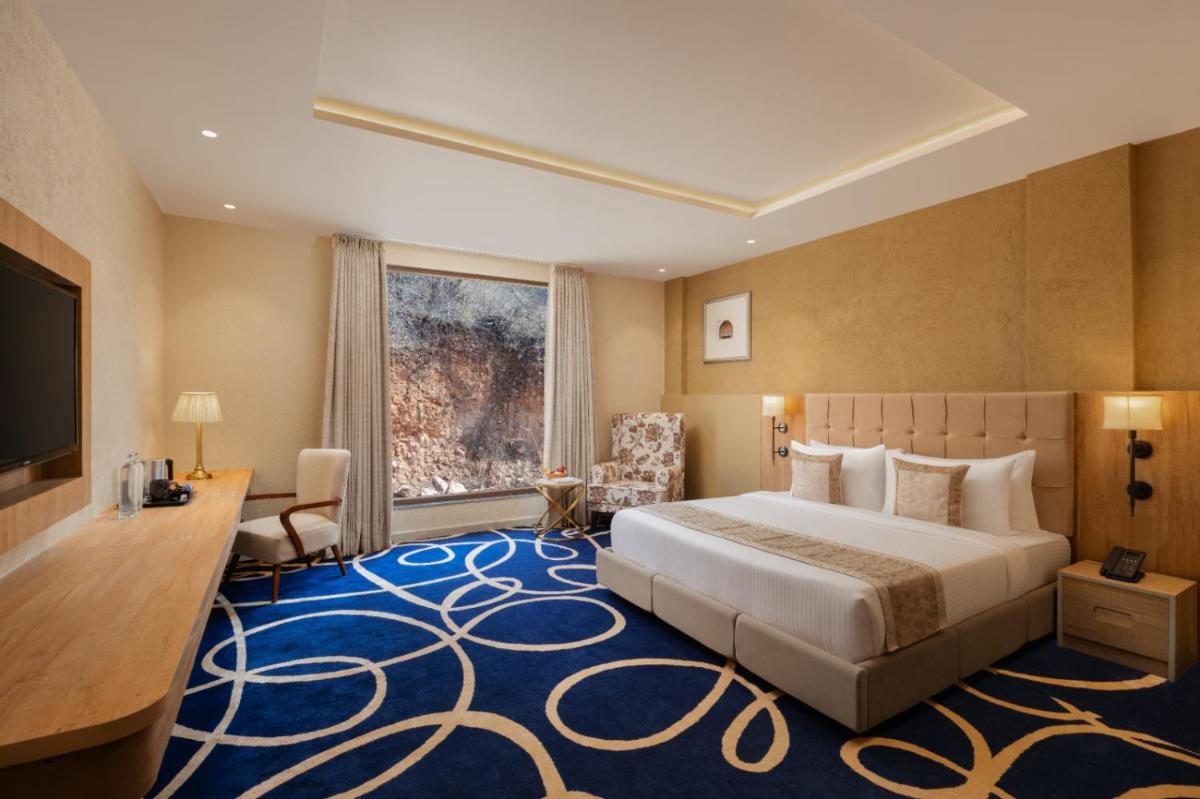 a hotel room with a large bed and a television at Essentia Luxury Resort & Spa Udaipur in Udaipur