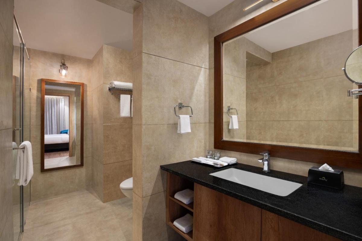 a bathroom with a sink and a mirror and a toilet at Essentia Luxury Resort & Spa Udaipur in Udaipur